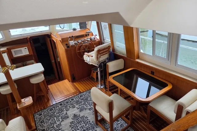 Slide: The Image of Interior of 2002 Mainship 430 Trawler with wooden helm, dining area, and nautical decor. - 6