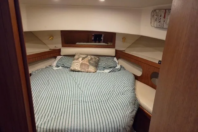 Slide: The Image of Cozy bedroom interior of 2002 Mainship 430 Trawler with striped bedding and wooden accents. - 11