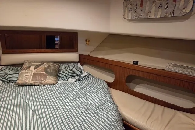 Slide: The Image of Cozy cabin interior of 2002 Mainship 430 Trawler with striped bedding and wooden accents. - 13