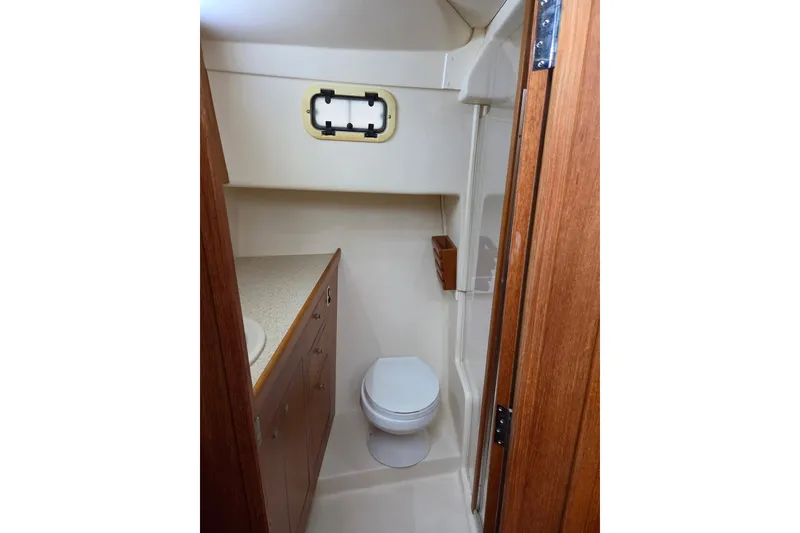 Slide: The Image of 2002 Mainship 430 Trawler bathroom with wooden cabinetry and compact design. - 14