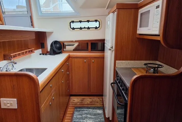 Slide: The Image of 2002 Mainship 430 Trawler kitchen with wood cabinetry, appliances, and countertop. - 9