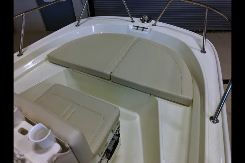 Slide: The Image of 2027 Boston Whaler 150 Montauk boat interior with cushioned seating and stainless steel railings. - 9