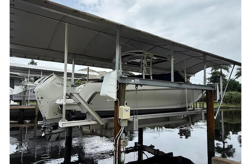 Slide: The Image of 2019 Boston Whaler 270 Vantage on a boat lift under a canopy. - 2