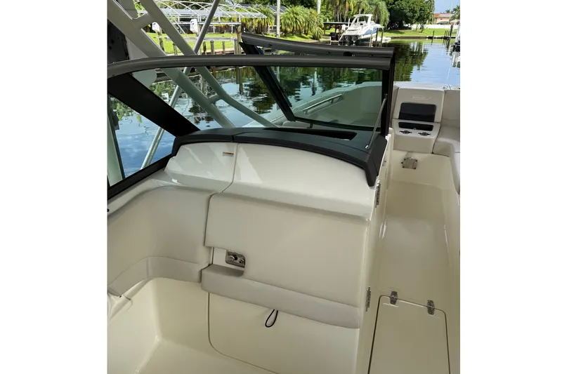 Slide: The Image of 2019 Boston Whaler 270 Vantage interior with seating and windshield, docked by a serene waterway. - 17