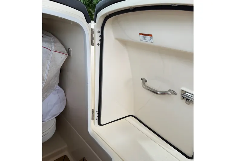 Slide: The Image of 2019 Boston Whaler 270 Vantage storage compartment with handle and safety label. - 31