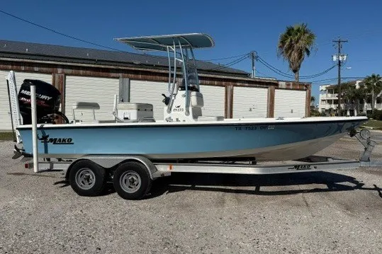The Image of 2015 Mako 21 LTS boat on trailer, parked outdoors under clear blue sky. - 0