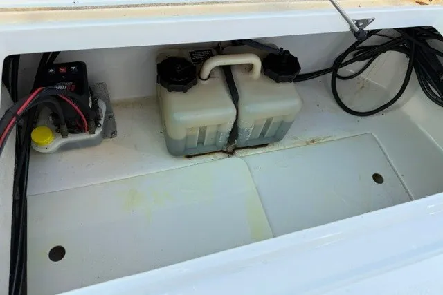 Slide: The Image of 2015 Mako 21 LTS boat battery compartment with wiring and dual batteries. - 14