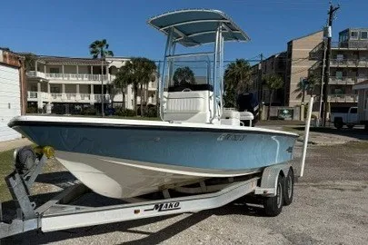 Slide: The Image of 2015 Mako 21 LTS boat on trailer, parked outdoors near buildings. - 2