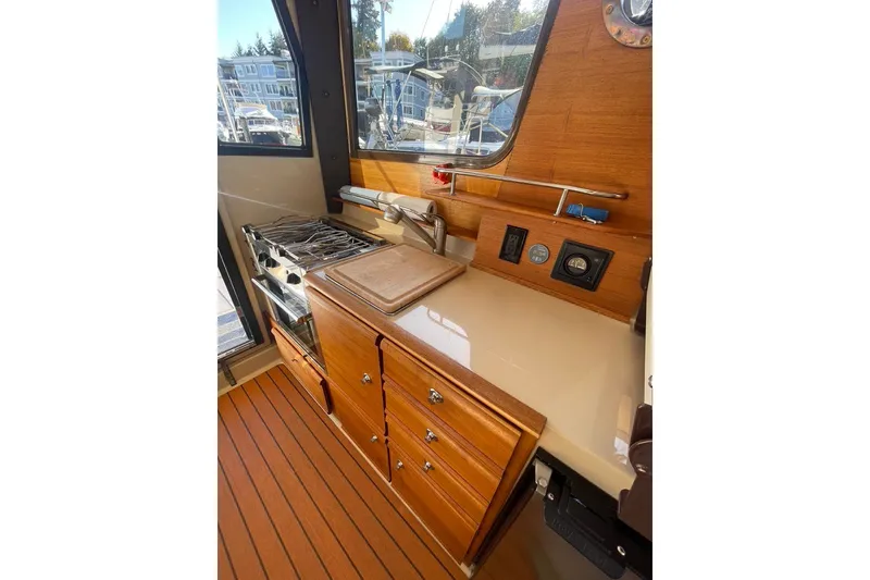 Slide: The Image of 2018 Ranger Tug R-27 interior kitchen with stove, wooden cabinetry, and countertop. - 13