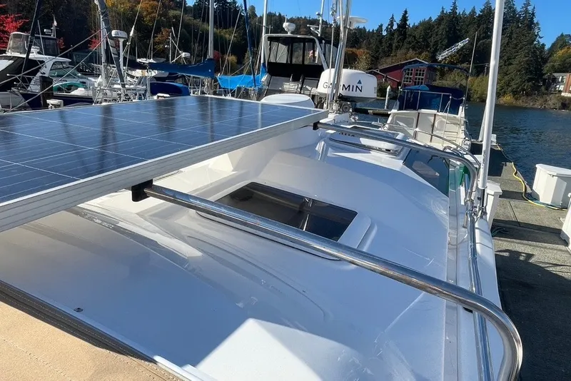 Slide: The Image of 2018 Ranger Tug R-27 with solar panel, docked in a marina, surrounded by boats and trees. - 36