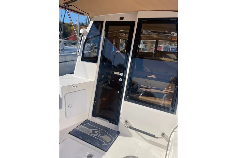 Slide: The Image of 2018 Ranger Tug R-27 boat entrance with glass door and outdoor seating area. - 5