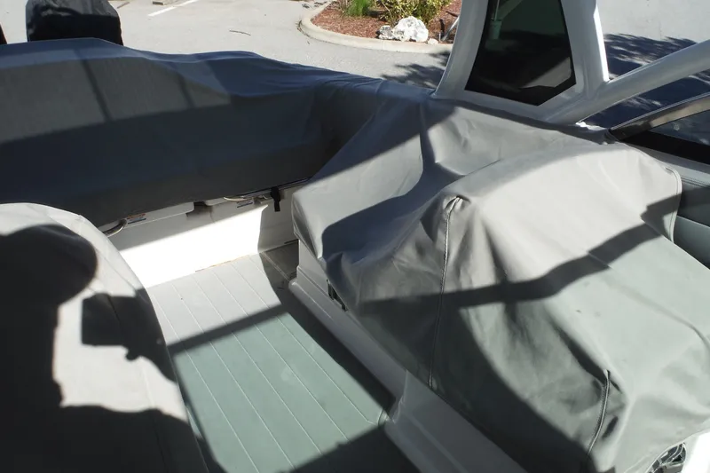 Slide: The Image of 2025 Chaparral 310 OSX boat interior with protective covers, showcasing seating and helm area. - 72