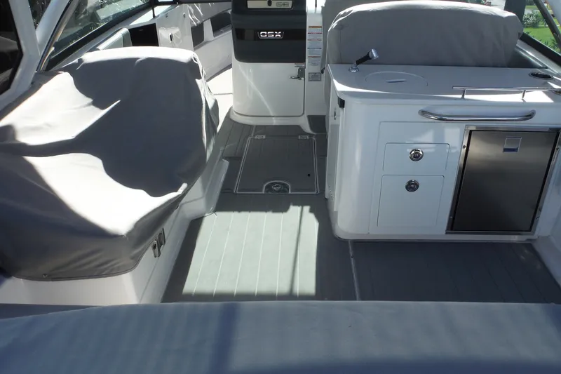 Slide: The Image of 2025 Chaparral 310 OSX boat interior with covered seating and kitchenette. - 69