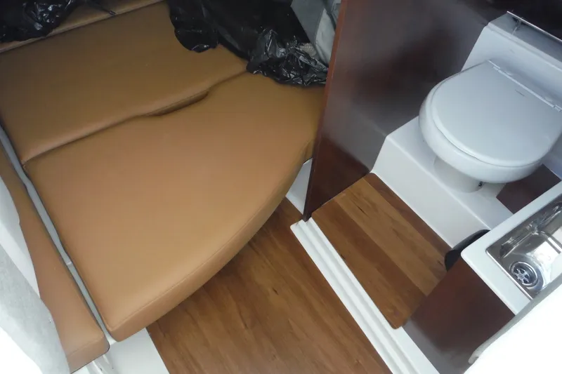 Slide: The Image of 2025 Chaparral 310 OSX cabin interior with bed, toilet, and sink. - 38