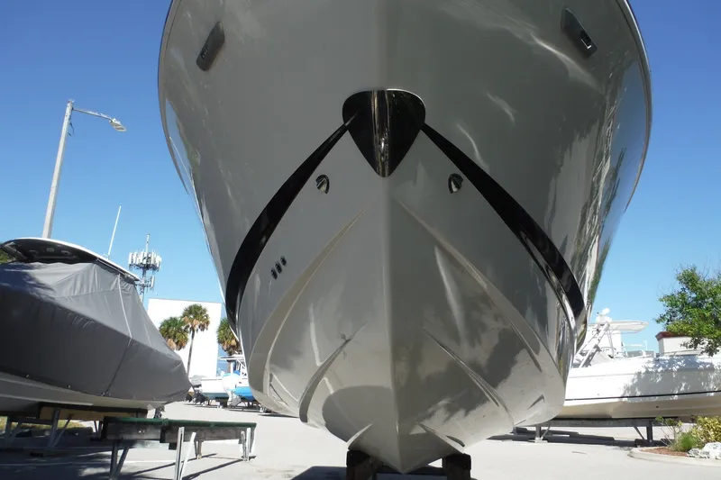 Slide: The Image of 2025 Chaparral 310 OSX boat front view, docked outdoors under clear blue sky. - 24