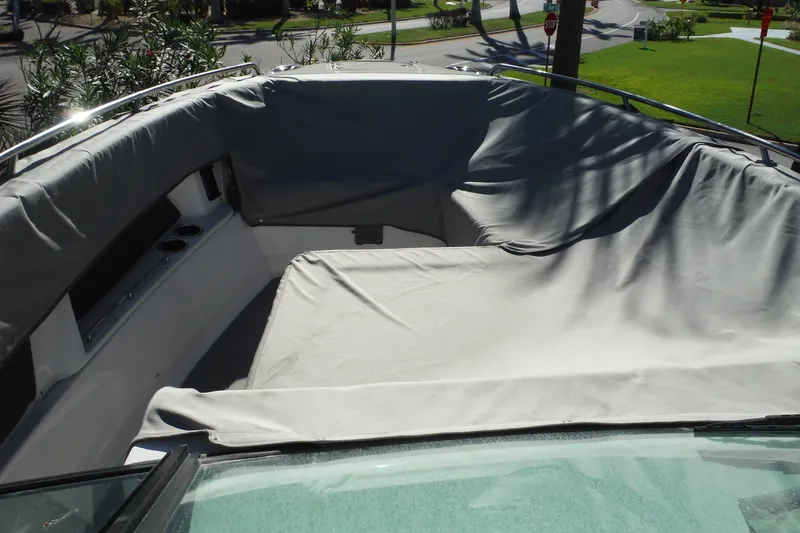 Slide: The Image of 2025 Chaparral 310 OSX boat with covered seating area, parked outdoors. - 71