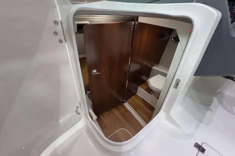 Slide: The Image of Manufacturer Provided Image: 2025 Chaparral 310 OSX boat interior with wooden door and compact bathroom. - 9