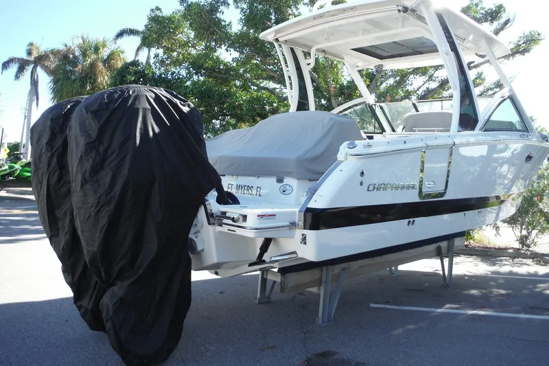 Slide: The Image of 2025 Chaparral 310 OSX boat on stands, covered engines, outdoor setting. - 74