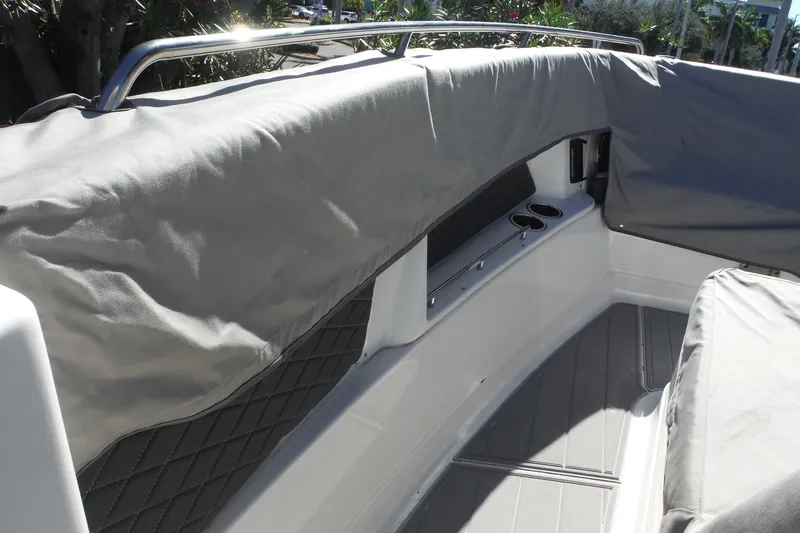 Slide: The Image of 2025 Chaparral 310 OSX boat interior with protective covers and cup holders. - 54