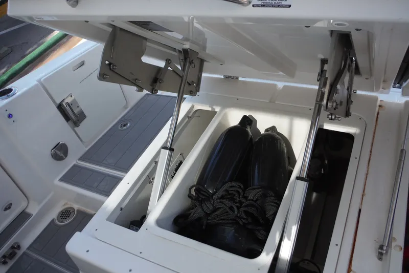 Slide: The Image of 2025 Chaparral 310 OSX boat storage compartment with fenders and ropes. - 45