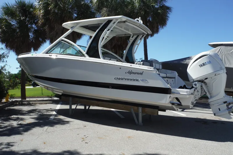 Slide: The Image of 2025 Chaparral 310 OSX boat with Yamaha engine, parked outdoors under palm trees. - 20