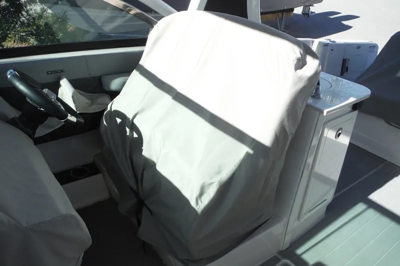 Slide: The Image of 2025 Chaparral 310 OSX boat interior with covered seats and steering wheel. - 56