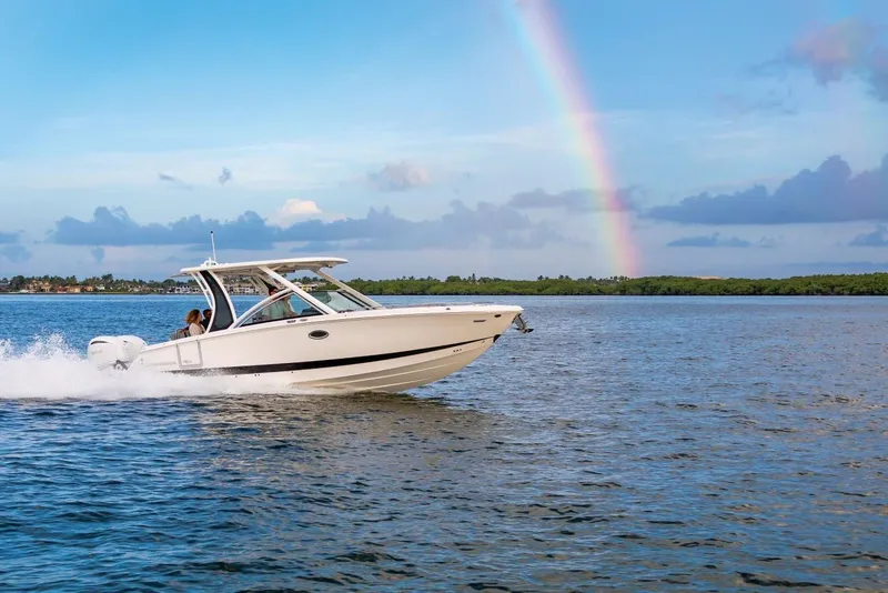 Slide: The Image of Manufacturer Provided Image: 2025 Chaparral 310 OSX boat cruising on water with a rainbow in the background. - 2