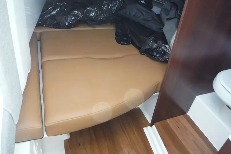 Slide: The Image of 2025 Chaparral 310 OSX cabin interior with tan cushions and wooden flooring. - 40