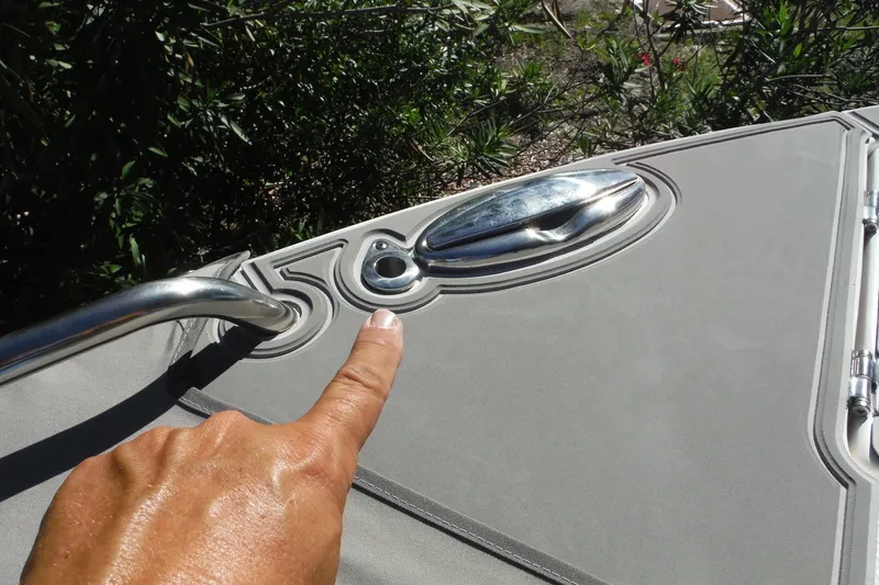 Slide: The Image of Close-up of a 2025 Chaparral 310 OSX boat deck with a hand pointing at a cleat. - 59