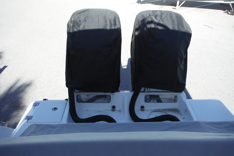 Slide: The Image of 2025 Chaparral 310 OSX boat with covered dual engines, docked on a sunny day. - 68