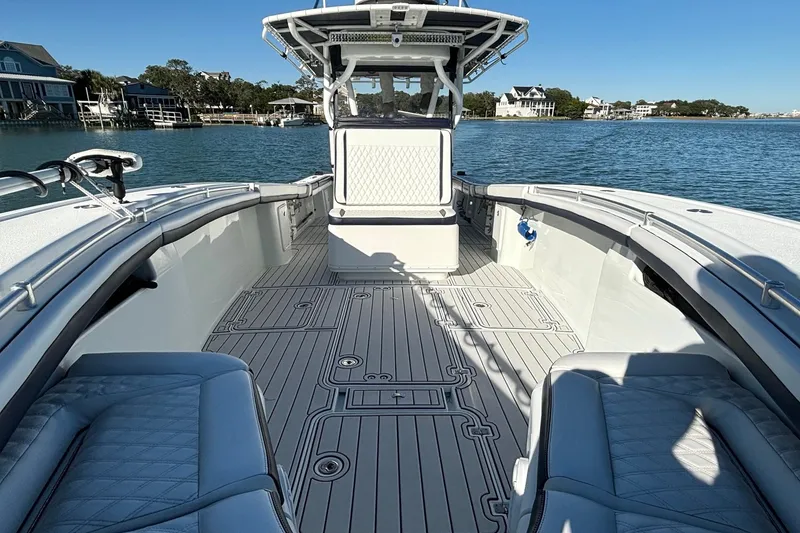 Slide: The Image of 2014 Yellowfin 34 Offshore boat with spacious deck and seating, docked by waterfront homes. - 19
