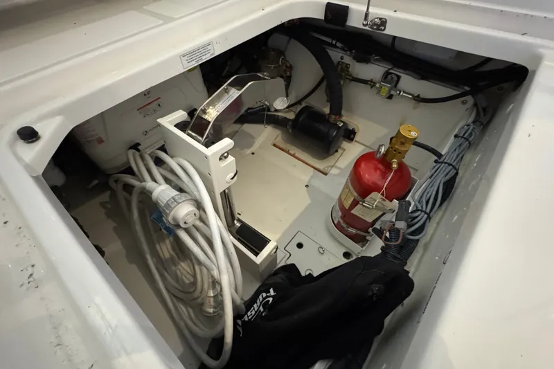 Slide: The Image of 2026 Pursuit DC 326 Dual Console boat storage compartment with equipment and fire extinguisher. - 16