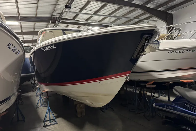 The Image of A 2026 Pursuit DC 326 Dual Console boat is stored on stands in a warehouse. - 0