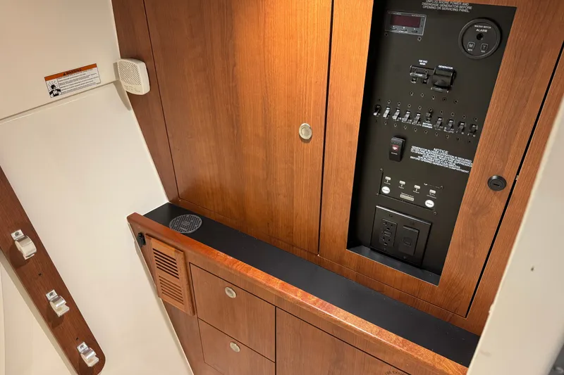 Slide: The Image of Electrical panel and wooden cabinetry inside a 2026 Pursuit DC 326 Dual Console boat. - 25