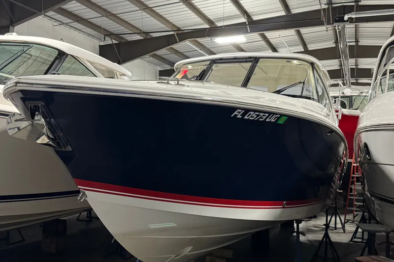 Slide: The Image of 2026 Pursuit DC 326 Dual Console boat in storage, featuring a sleek navy and white design. - 4
