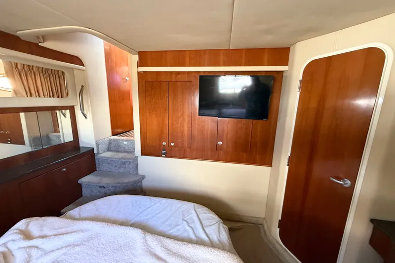 Slide: The Image of 2005 Sea Ray 390 Motor Yacht interior with wood paneling, TV, and stairs. - 25