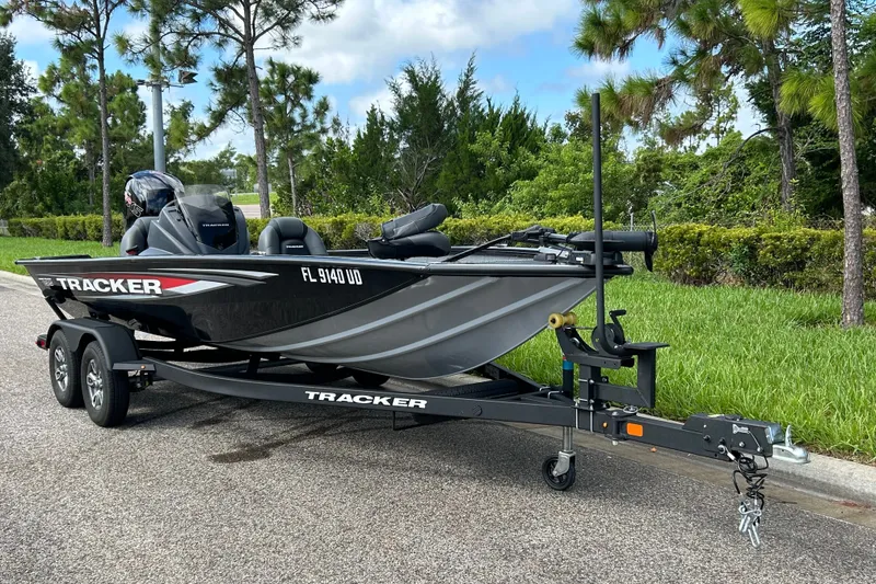The Image of 2026 Tracker Pro Team 195 boat on trailer, parked roadside with trees in background. - 0