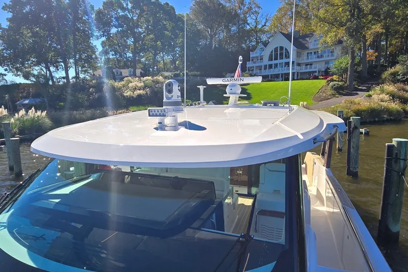 Slide: The Image of 2026 Tiara Yachts 56 LS docked near a waterfront property with lush greenery. - 35