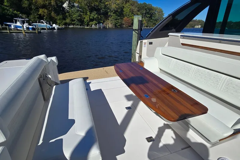 Slide: The Image of Luxury seating area on 2026 Tiara Yachts 56 LS, featuring elegant wooden table by the water. - 20