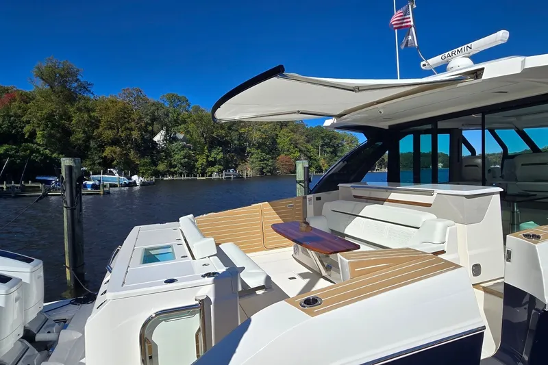 Slide: The Image of 2026 Tiara Yachts 56 LS luxury yacht interior with seating and table, docked by a scenic river. - 13