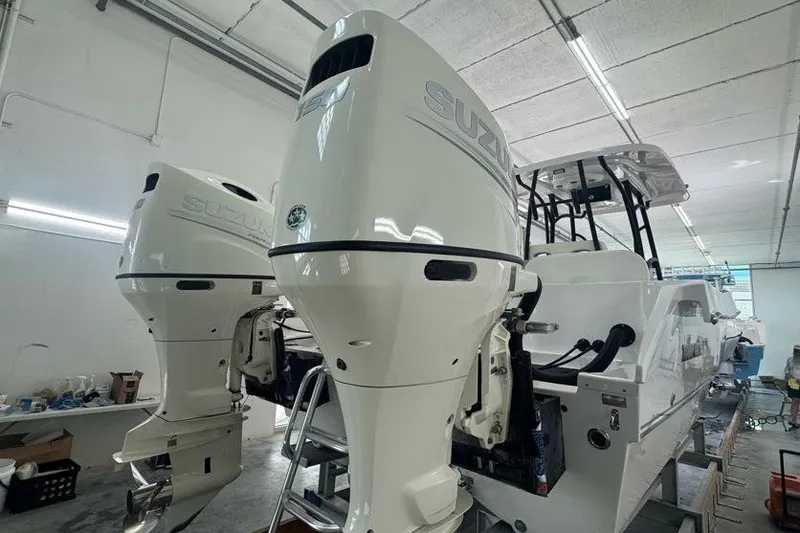 Slide: The Image of 2020 Twin Vee 260 CC SE boat with dual Suzuki outboard motors in a workshop. - 18
