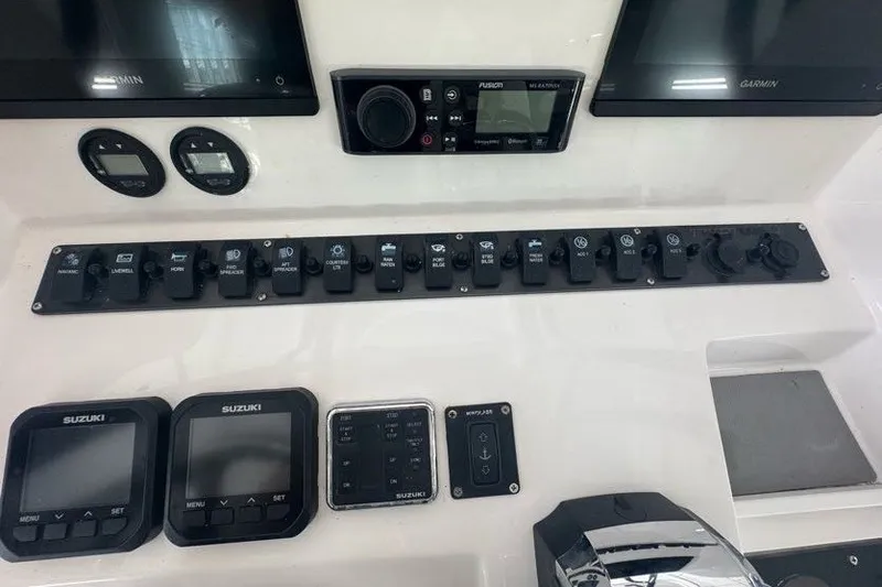 Slide: The Image of Control panel of a 2020 Twin Vee 260 CC SE boat with various switches and displays. - 32