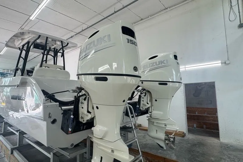 Slide: The Image of 2020 Twin Vee 260 CC SE boat with dual Suzuki 150 outboard engines in a workshop. - 20