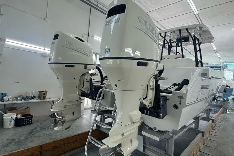 Slide: The Image of 2020 Twin Vee 260 CC SE boat with dual Suzuki outboard motors in a workshop. - 19