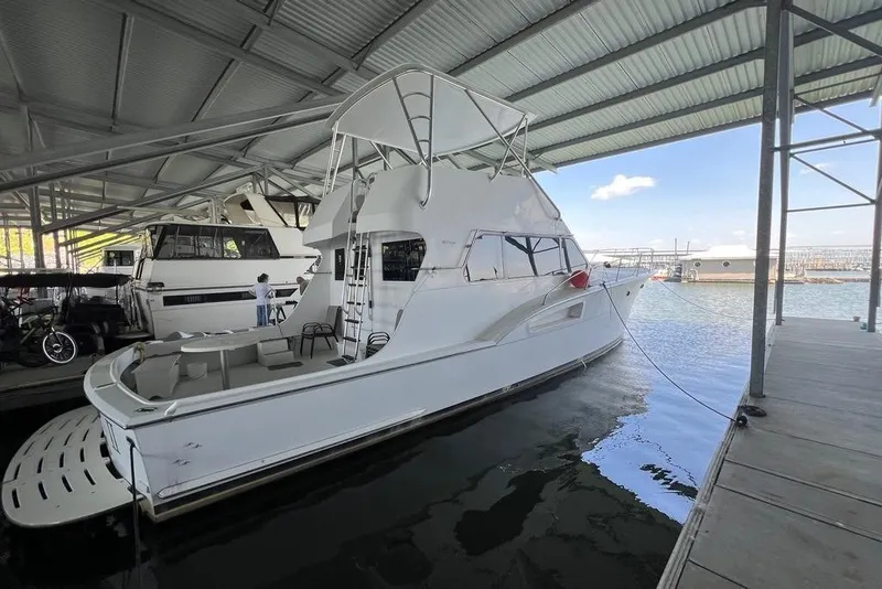 Slide: The Image of A white 1976 Hatteras 53 Convertible is docked under a covered marina. - 9