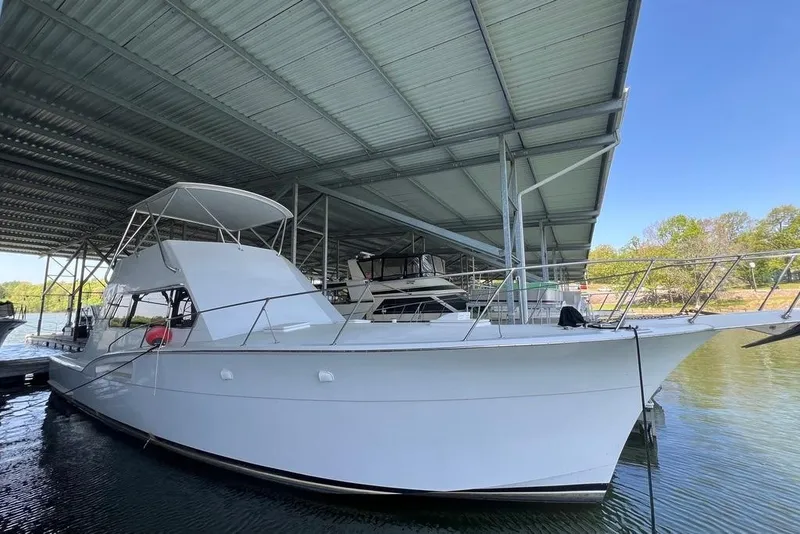Slide: The Image of A white 1976 Hatteras 53 Convertible docked in a covered marina area. - 12