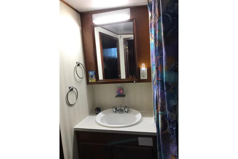 Slide: The Image of A bathroom with a sink, mirror, and colorful shower curtain in a boat. - 27