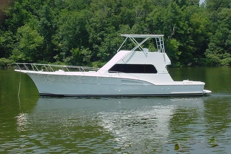 Slide: The Image of A 1976 Hatteras 53 Convertible on calm water, surrounded by trees. - 1