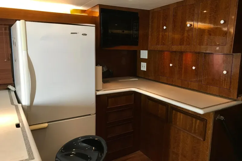 Slide: The Image of The kitchen of a 1976 Hatteras 53 Convertible with wooden cabinets and a large refrigerator. - 14