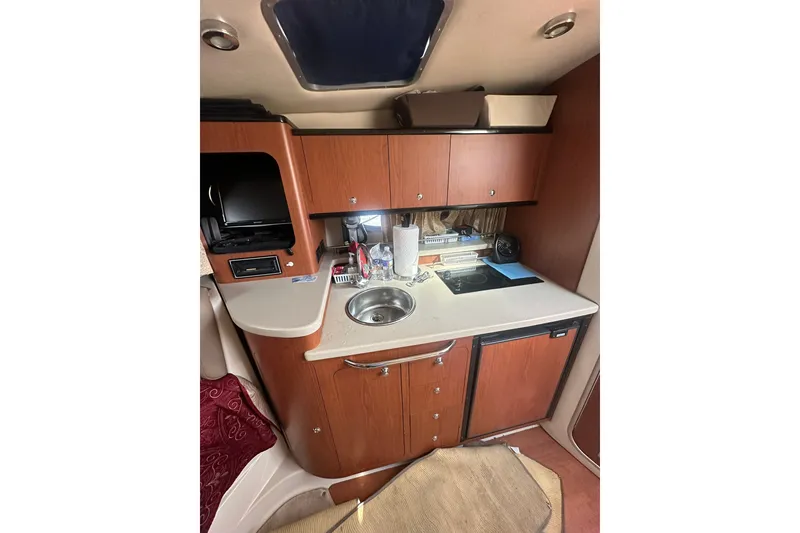 Slide: The Image of 2002 Chaparral Signature 320 boat interior kitchen with sink, stove, and wooden cabinets. - 19